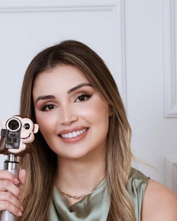 Dra. Alexia Caldas, oftalmologista, sorrindo, com um oftalmoscópio de capa infantil na mão